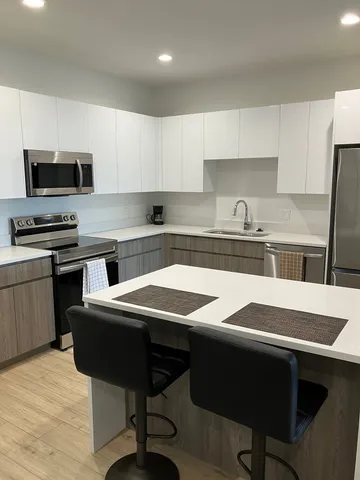 a kitchen with stainless steel appliances granite countertop a refrigerator a sink a stove and island