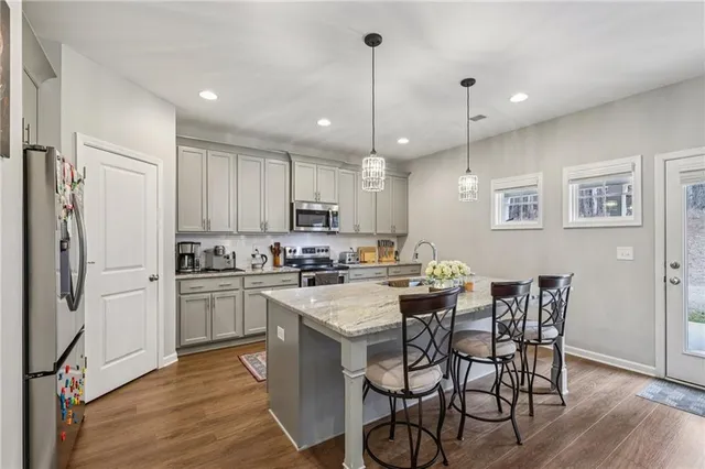 a kitchen with stainless steel appliances granite countertop a dining table chairs stove refrigerator and cabinets