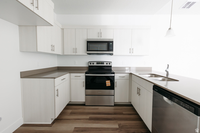 4653 South Alder Drive, Unit H304 Mapleton, UT 84664 - Photo 7 of 14 Kitchen with stainless steel appliances, dark wood-style flooring, white cabinets, pendant lighting, and a peninsula