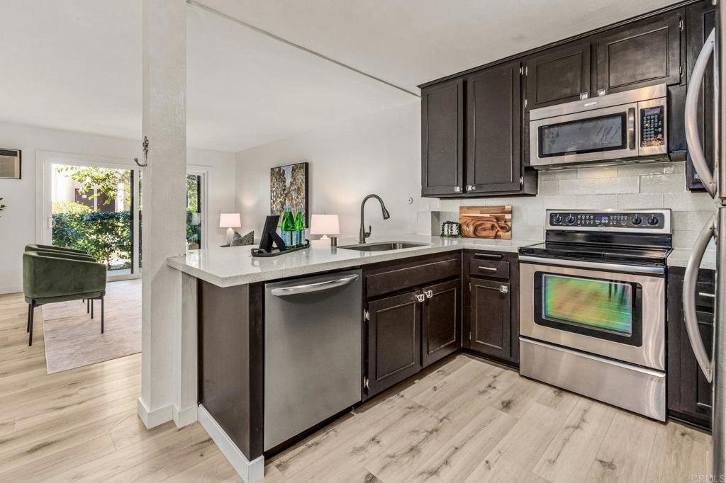 6780 Friars Road, Unit 129 San Diego, CA 92108 - Photo 10 of 50 a kitchen with kitchen island granite countertop a sink cabinets and stainless steel appliances