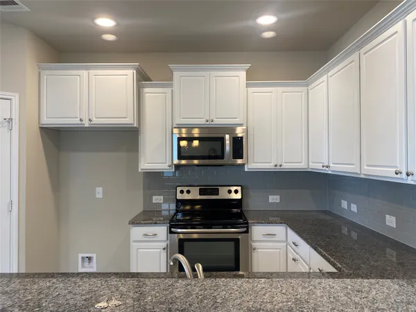 a kitchen with granite countertop a sink a stove and cabinets
