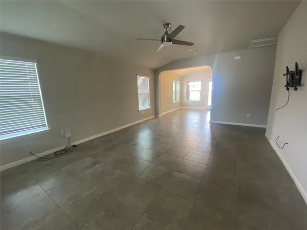 an empty room with windows and ceiling fan