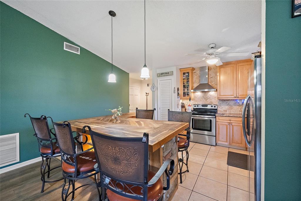 1056 Hope Street Venice, FL 34285 - Photo 7 of 27 a kitchen with stainless steel appliances kitchen island granite countertop a table chairs and a wooden floor