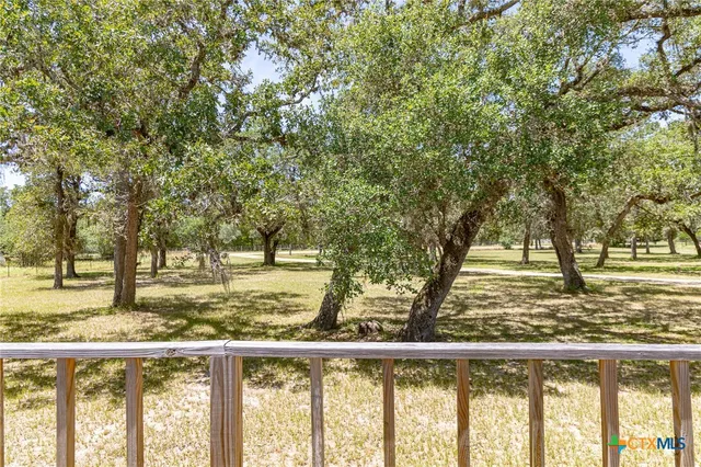 a view of a yard with wooden fence and large trees