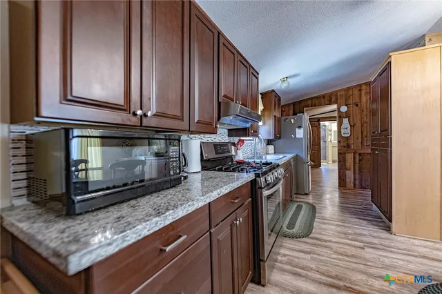 a kitchen with stainless steel appliances granite countertop a stove a sink and a microwave