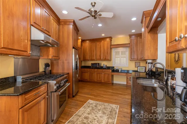 a kitchen with stainless steel appliances granite countertop a stove a sink dishwasher and cabinets with wooden floor