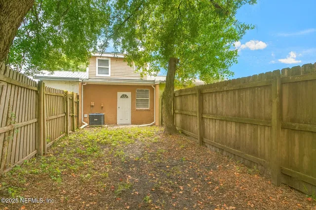 a view of backyard of house with wooden fence