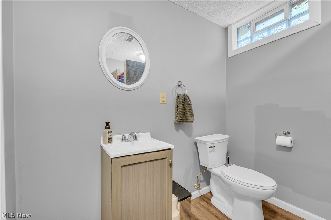 408 River Road Canal Fulton, OH 44614 - Photo 36 of 42 Powder room featuring a wood-finish vanity with an integrated sink, an oval wall-mounted mirror, and wood-look flooring