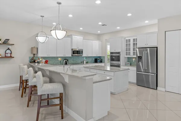 a kitchen with stainless steel appliances kitchen island granite countertop a table chairs refrigerator and microwave
