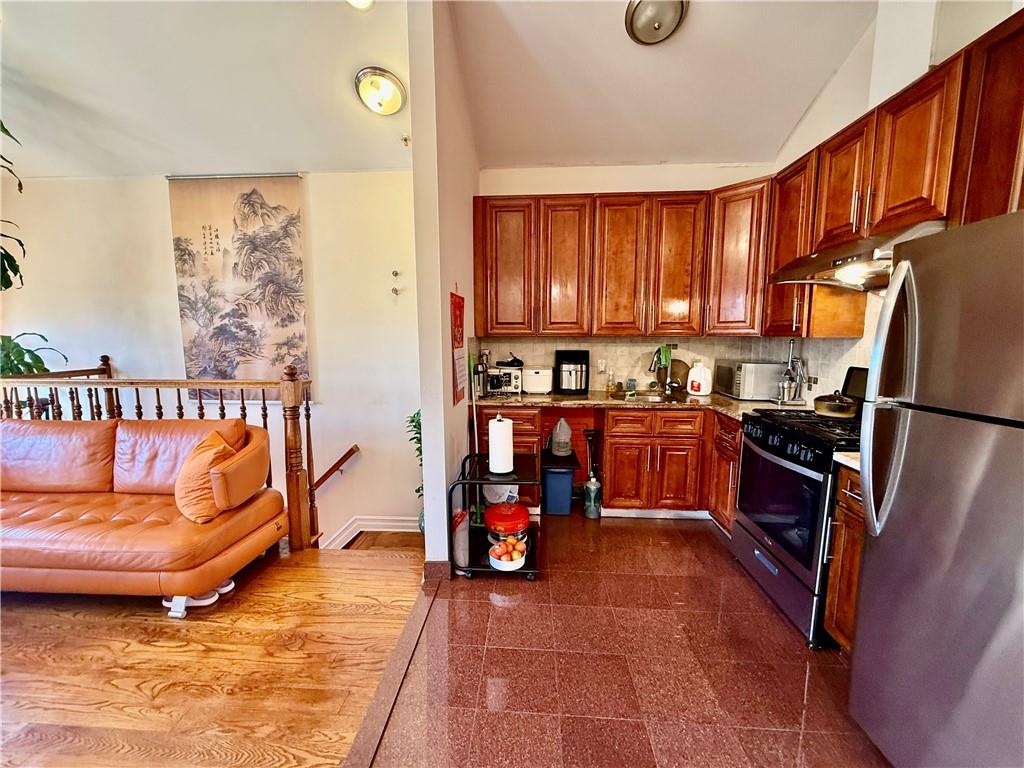 8752 18th Avenue, Unit 3E Brooklyn, NY 11214 - Photo 4 of 15 a kitchen with granite countertop a refrigerator and a stove top oven