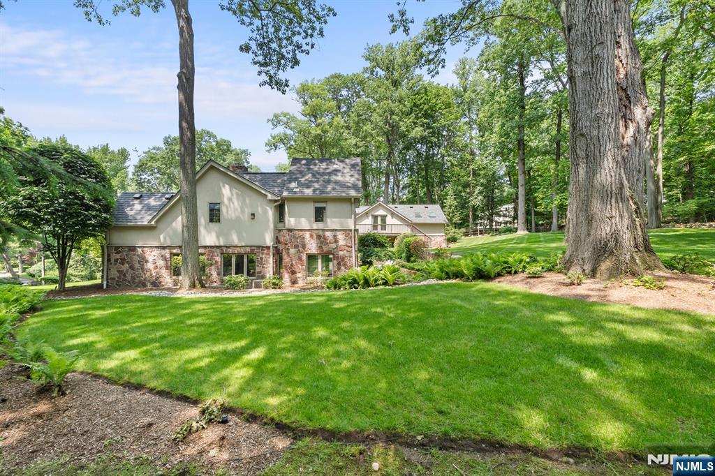 67 Forest Road Tenafly, NJ 07670 - Photo 34 of 42 a view of a white house in front of a big yard with large trees
