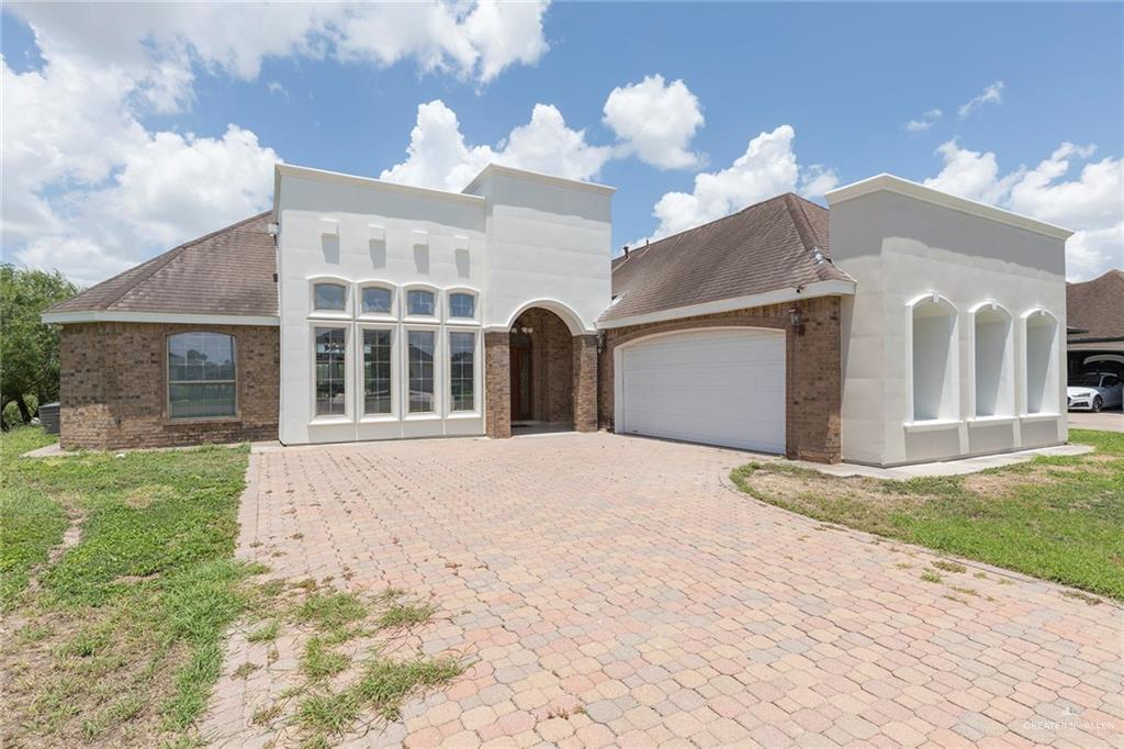 1213 Rhett Drive Pharr, TX 78577 - Photo 2 of 19 Beautiful front elevation with stucco and brick exterior, paver driveway, and two-car garage.