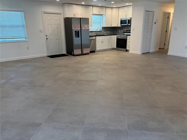 a view of a kitchen with stainless steel appliances granite countertop a refrigerator and a stove top oven