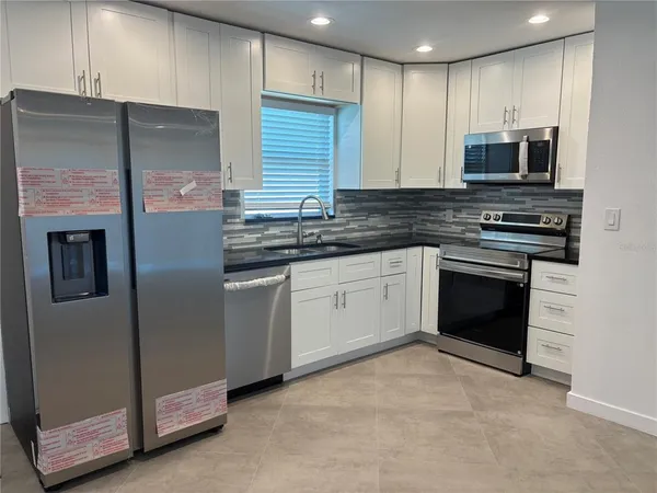 a kitchen with stainless steel appliances granite countertop a stove a sink and a microwave