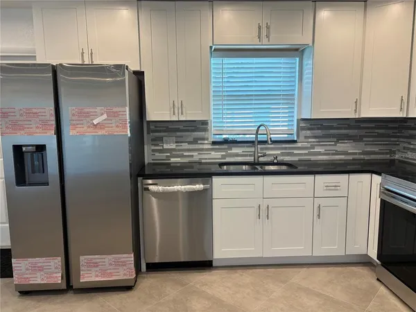 a kitchen with stainless steel appliances granite countertop a refrigerator and a sink