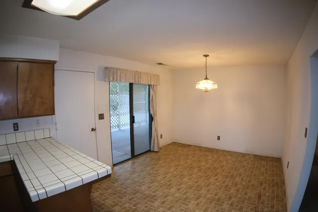 an empty room with chandelier fan and wooden floor