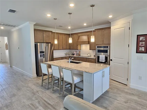 a kitchen with stainless steel appliances granite countertop a refrigerator a stove a sink dishwasher and a refrigerator with wooden floor