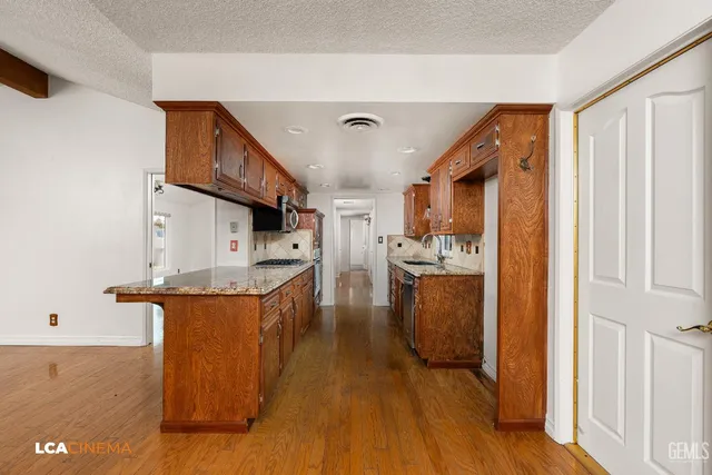 a kitchen with stainless steel appliances granite countertop a lot of cabinets and wooden floor