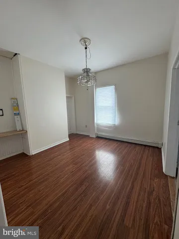 an empty room with wooden floor chandelier and windows