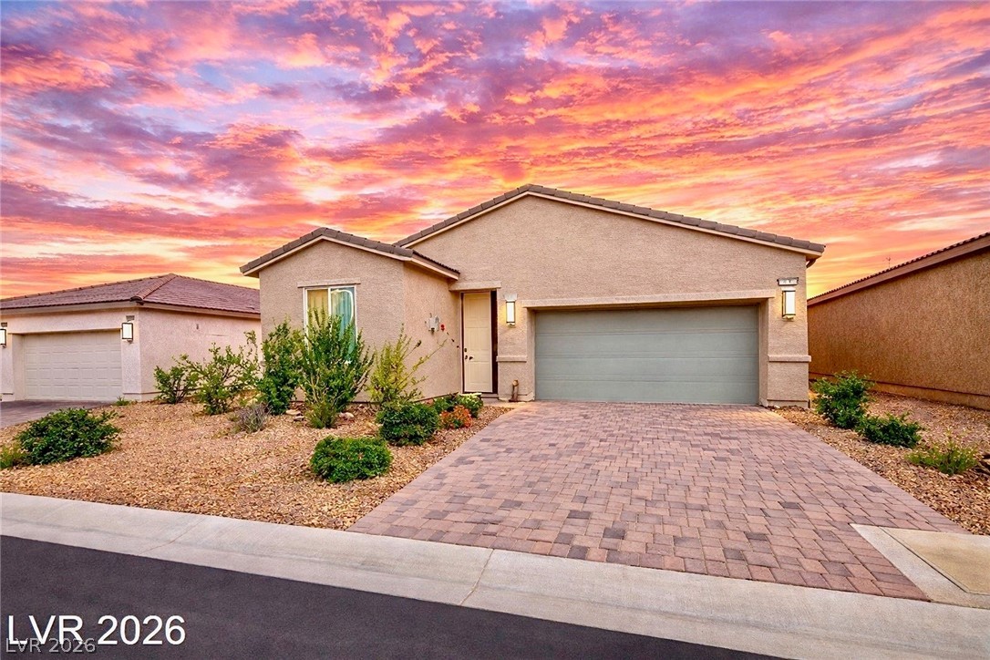 Single story home featuring stucco siding, a garage, and driveway