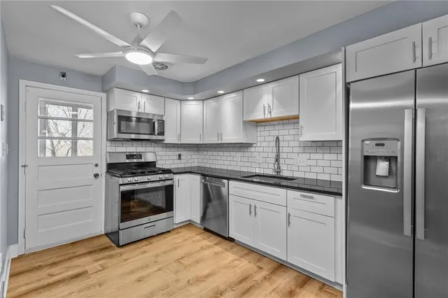 a kitchen with stainless steel appliances granite countertop a sink a stove a refrigerator cabinets and a window