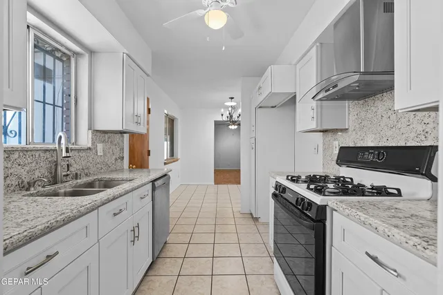 a kitchen with stainless steel appliances granite countertop a stove a sink and a white cabinets
