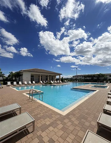 a view of a swimming pool with lawn chairs with plants