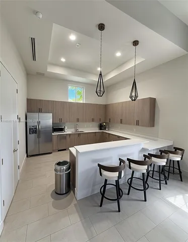a kitchen with refrigerator a sink and chairs