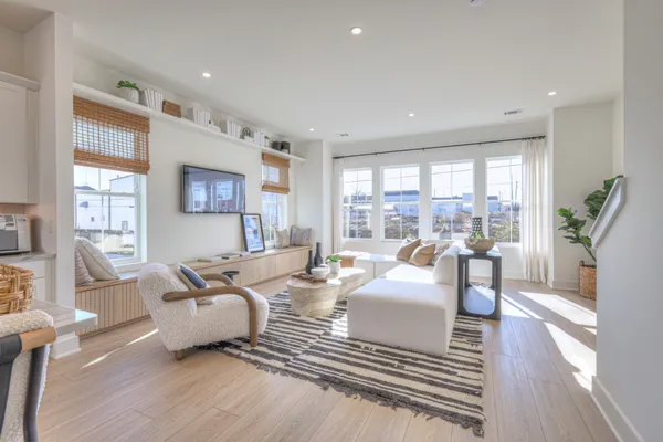 a living room with furniture large windows and wooden floor