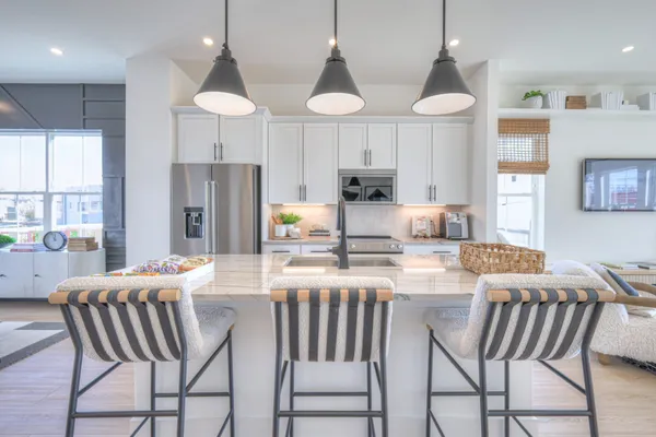 a kitchen with stainless steel appliances a dining table chairs and a refrigerator