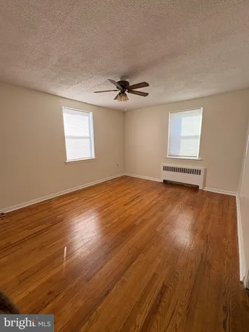 an empty room with wooden floor chandelier fan and windows