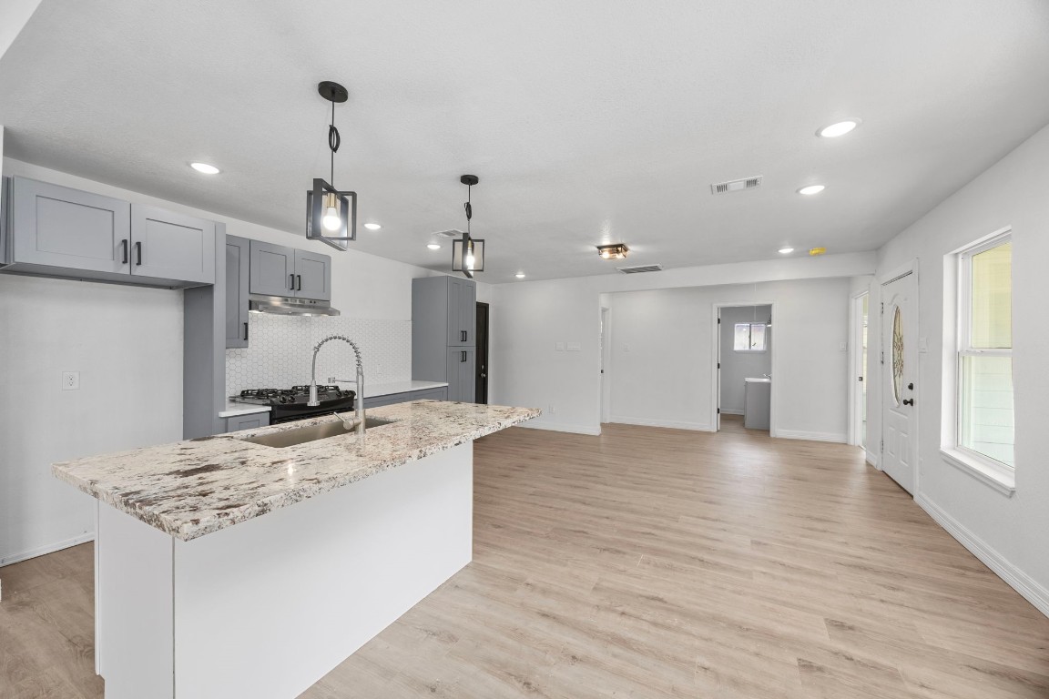 905 Elm Avenue Pasadena, TX 77506 - Photo 9 of 21 a large kitchen with kitchen island a stove a sink a refrigerator and white cabinets with wooden floor