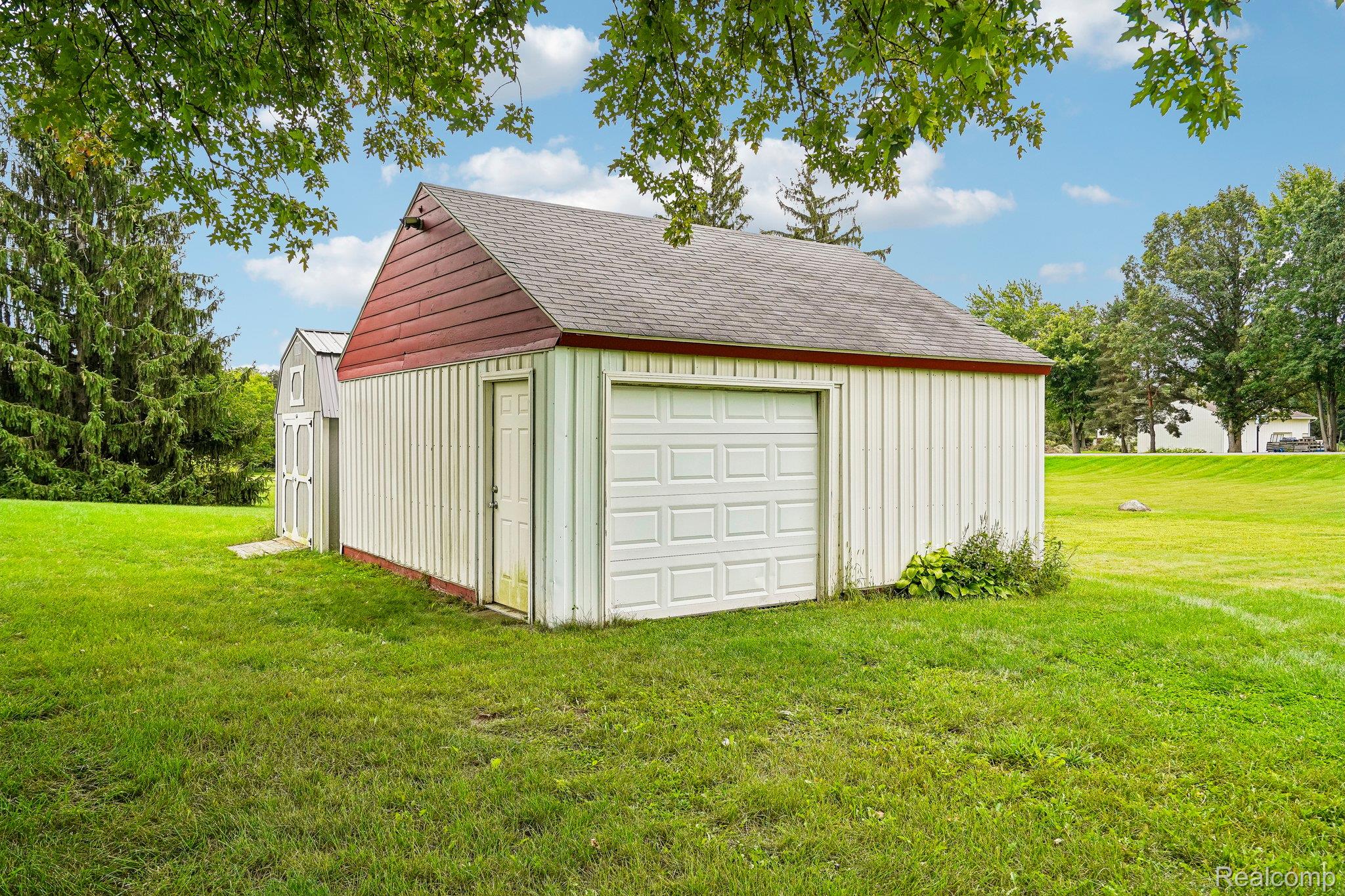 3981 South State Road Durand, MI 48429 - Photo 25 of 33 Detached outbuilding with a single garage door, an entry door, and a shed-style roof