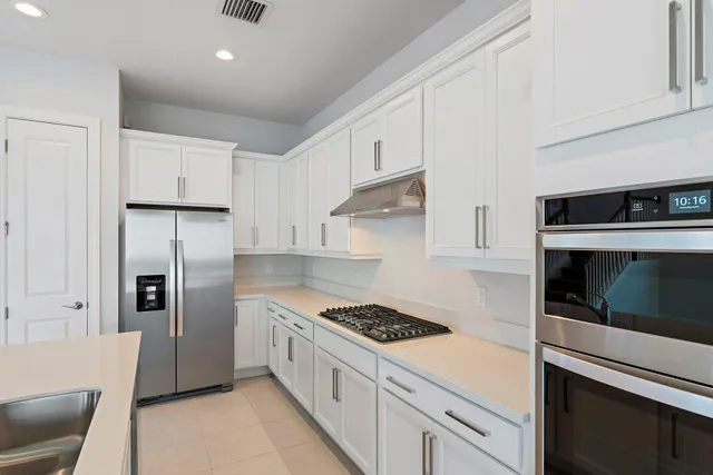 a view of an empty room with kitchen and window