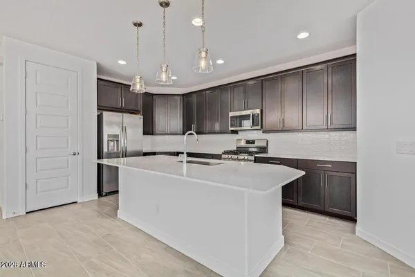 a large white kitchen with kitchen island a sink a stove a refrigerator and cabinets