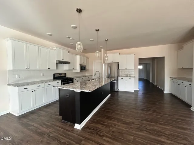 a large kitchen with stainless steel appliances granite countertop a lot of counter space and wooden floors