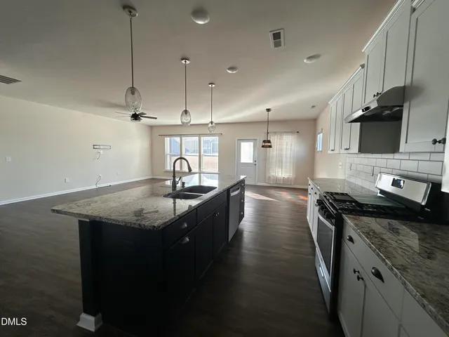 a kitchen with stainless steel appliances granite countertop a sink a stove and a wooden floors