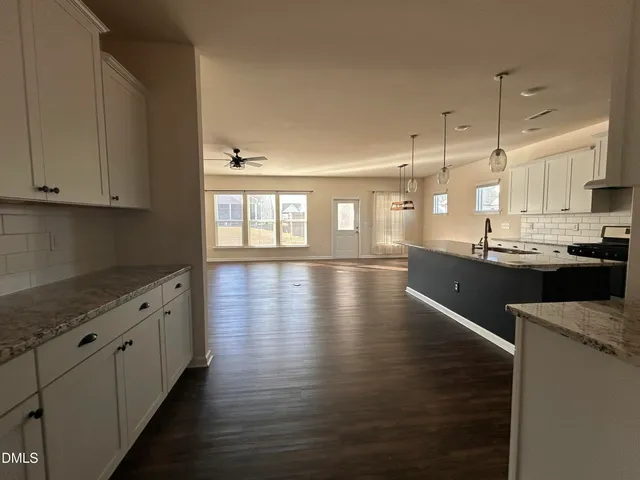 a kitchen with stainless steel appliances granite countertop a stove a sink and white cabinets