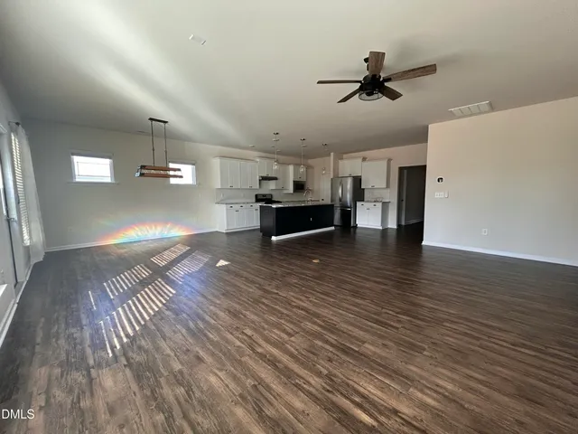 a view of a room with wooden floor a ceiling fan and windows