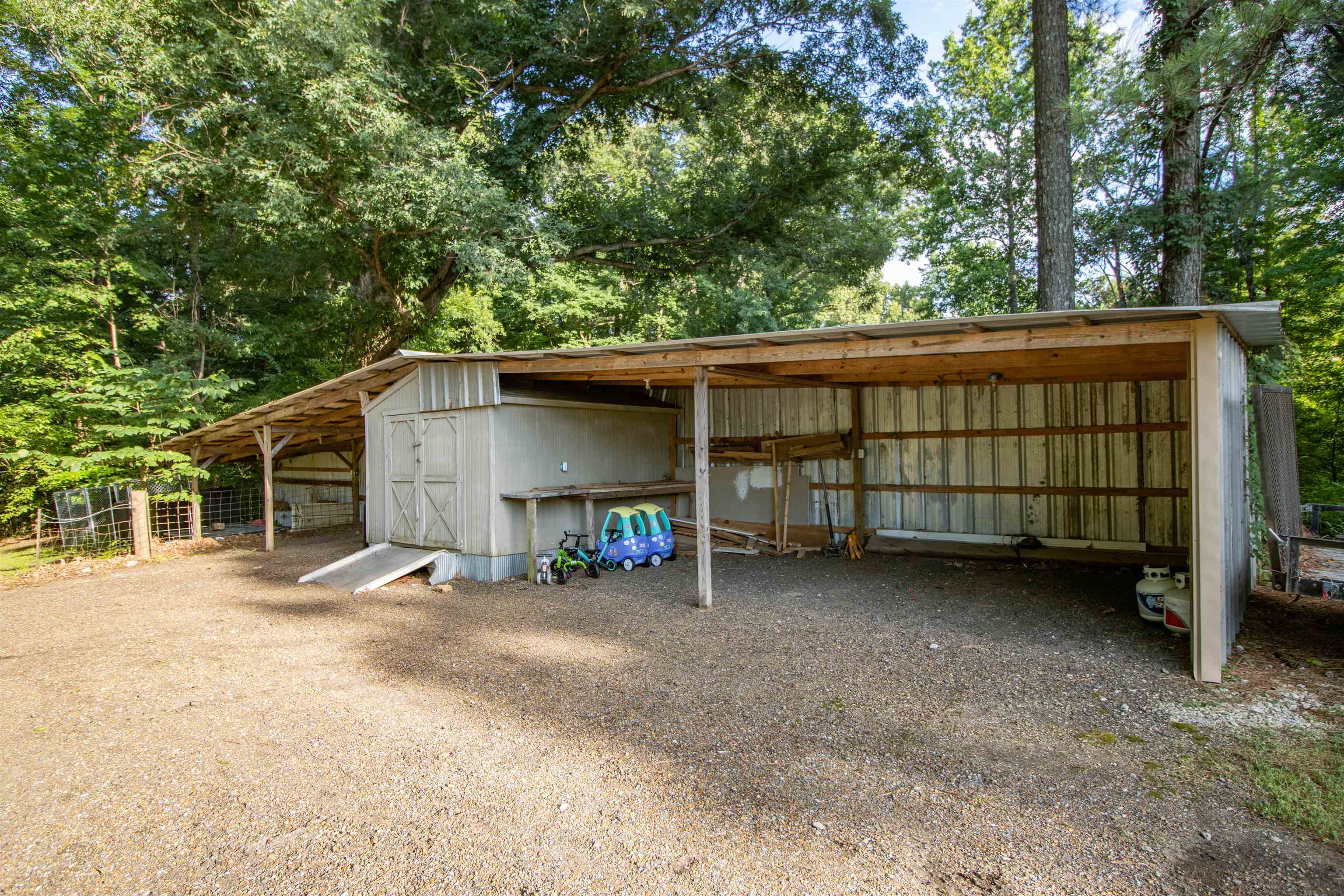 120 Craig Road Ripley, TN 38063 - Photo 26 of 38 Detached storage building featuring a covered lean-to, dual entry doors, wood-frame construction, and a corrugated metal exterior