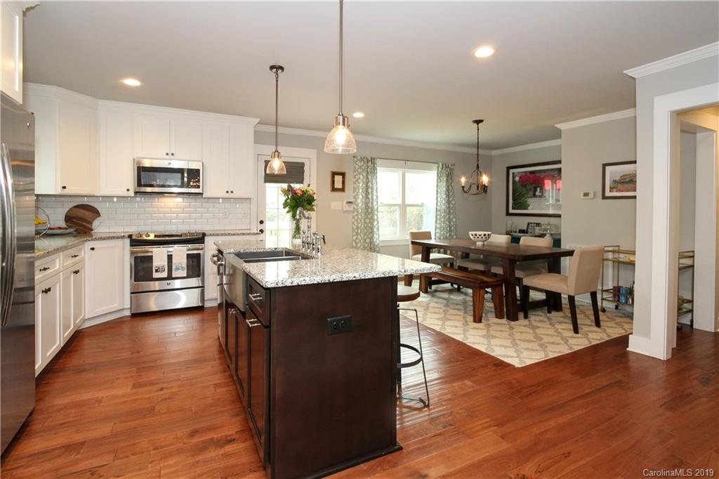 4217 Walker Road Charlotte, NC 28211 - Photo 11 of 34 a kitchen with stainless steel appliances kitchen island granite countertop a stove top oven a sink a dining table and chairs with wooden floor