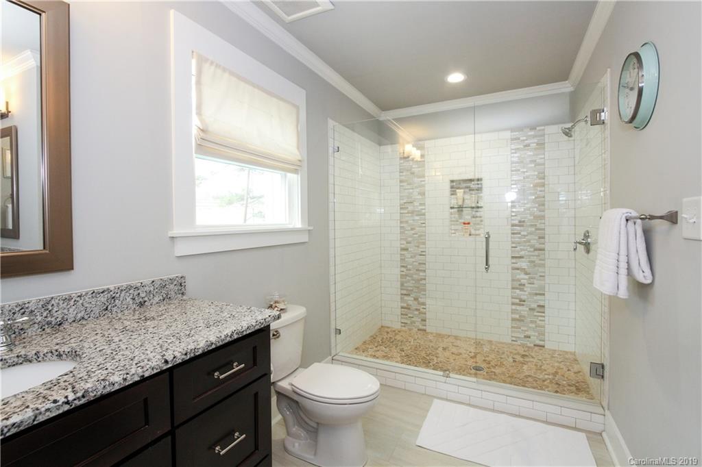 4217 Walker Road Charlotte, NC 28211 - Photo 17 of 34 a bathroom with a granite countertop sink a toilet a mirror and shower