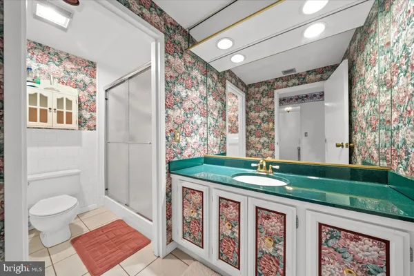 a bathroom with a granite countertop sink a toilet a mirror a vanity and shower