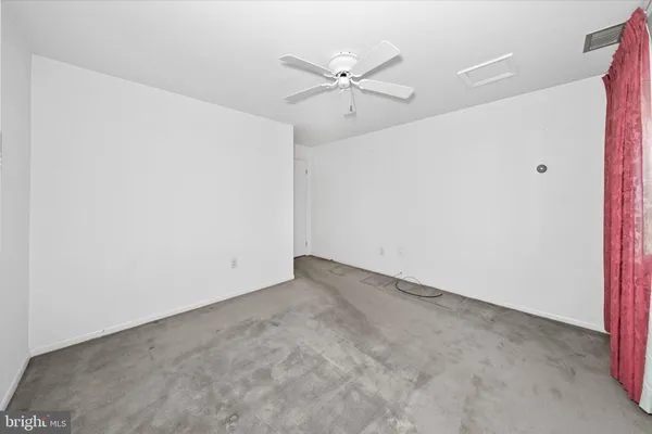 an empty room with a ceiling fan and a window