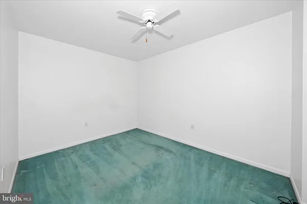 an empty room with a fan & a ceiling fan