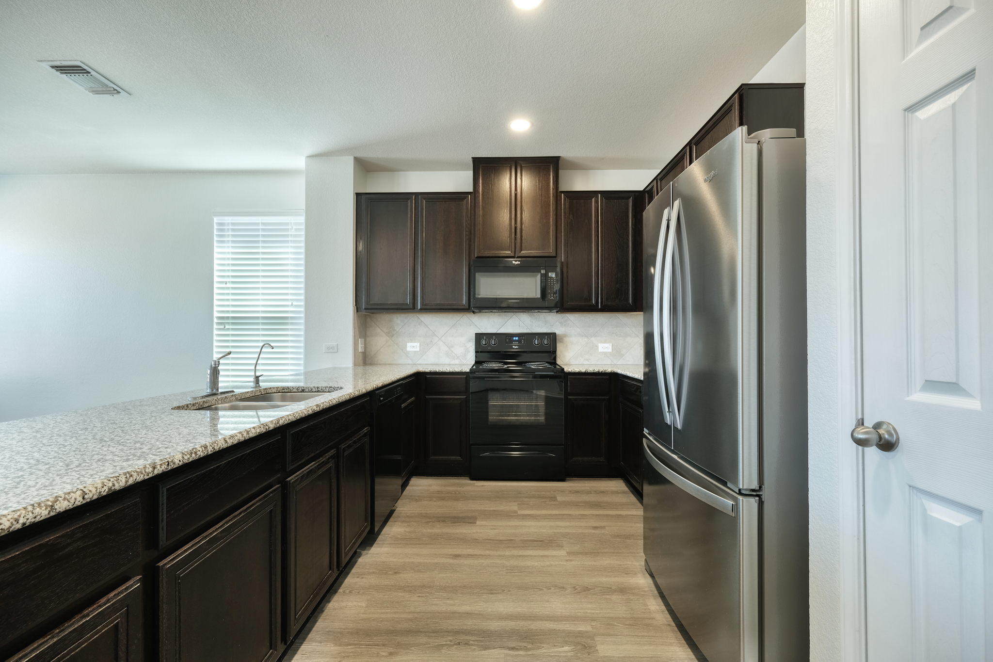 13813 James Garfield Street Manor, TX 78653 - Photo 7 of 13 a kitchen with a refrigerator and a sink