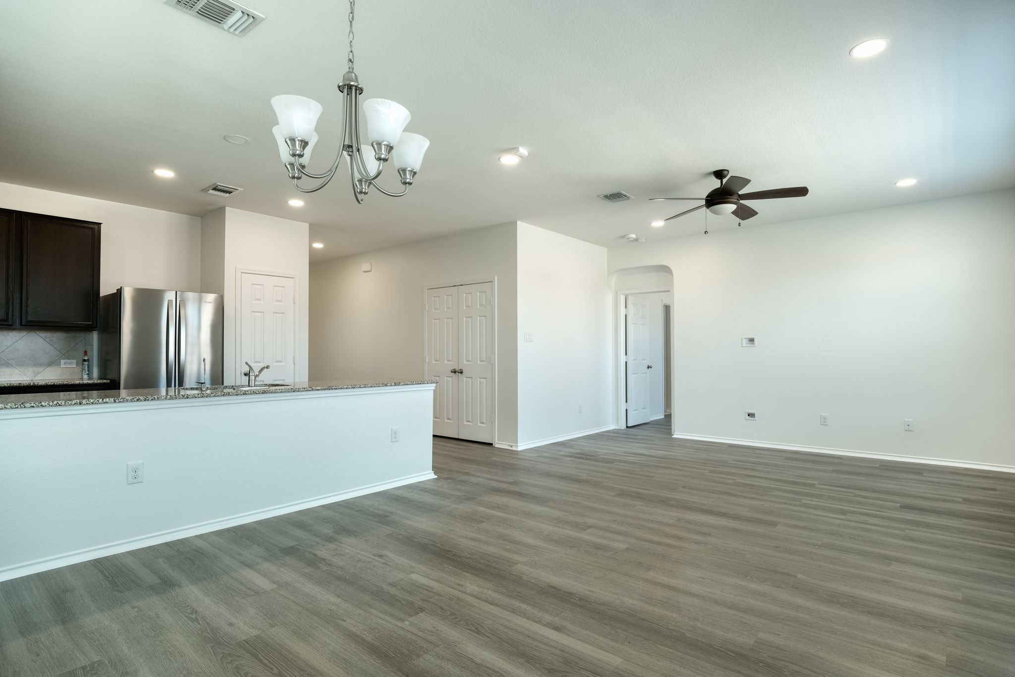13813 James Garfield Street Manor, TX 78653 - Photo 9 of 13 an empty room with wooden floor and a ceiling fan