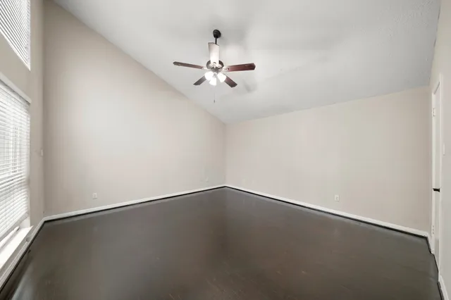 an empty room with a window and ceiling fan