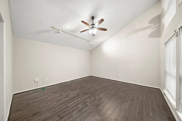 an empty room with wooden floor fan and windows