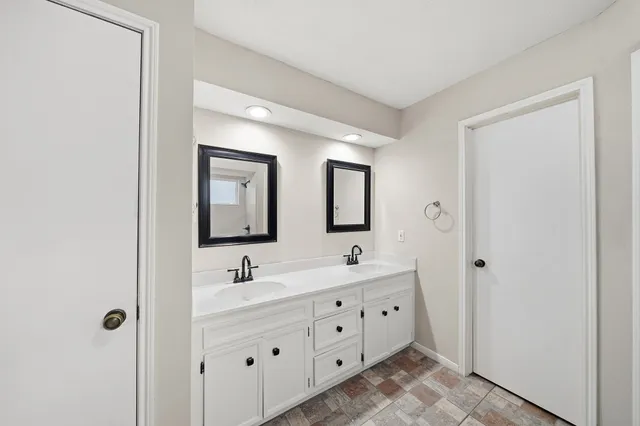 a bathroom with double sink and three mirror